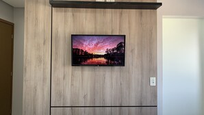 A flat-screen TV mounted on a wooden wall with a built-in shelf above it. - HOTEL SEVEN (Goiânia)