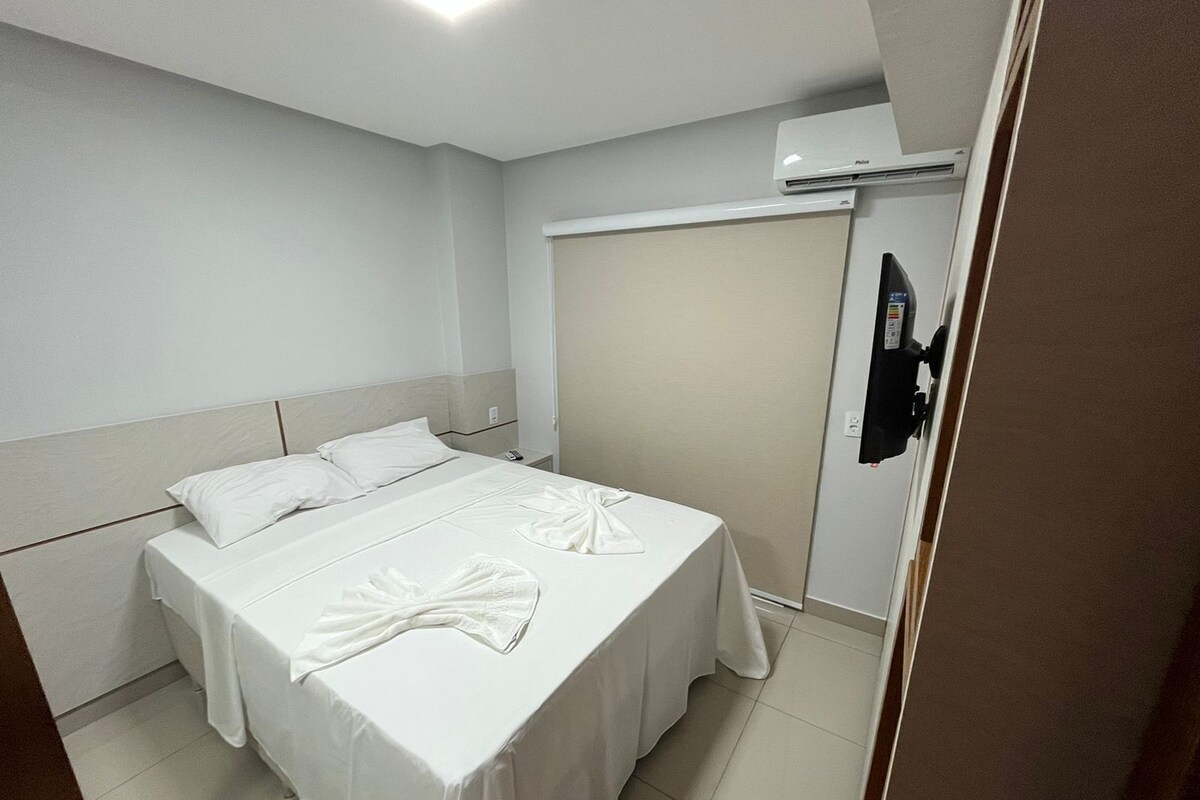 A hotel room with a bed, a wardrobe, and an air conditioning unit.