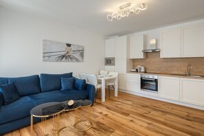 Un salon moderne avec un canapé bleu, une table basse et un coin repas comprenant une table et des chaises blanches.