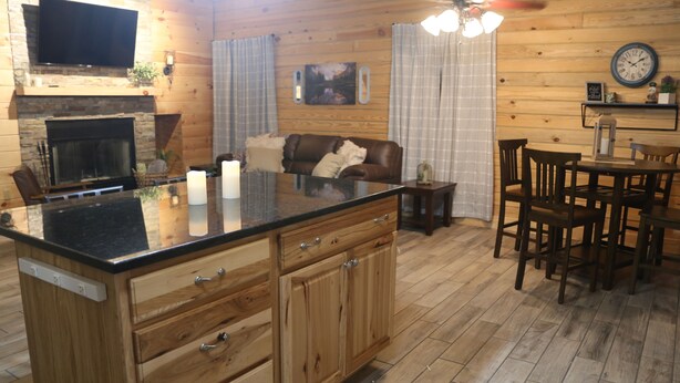 Ein Holzinterieur mit Kücheninsel, Esstisch und Stühlen.