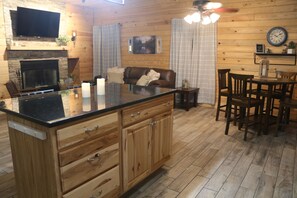 Ein Holzinterieur mit Kücheninsel, Esstisch und Stühlen.
