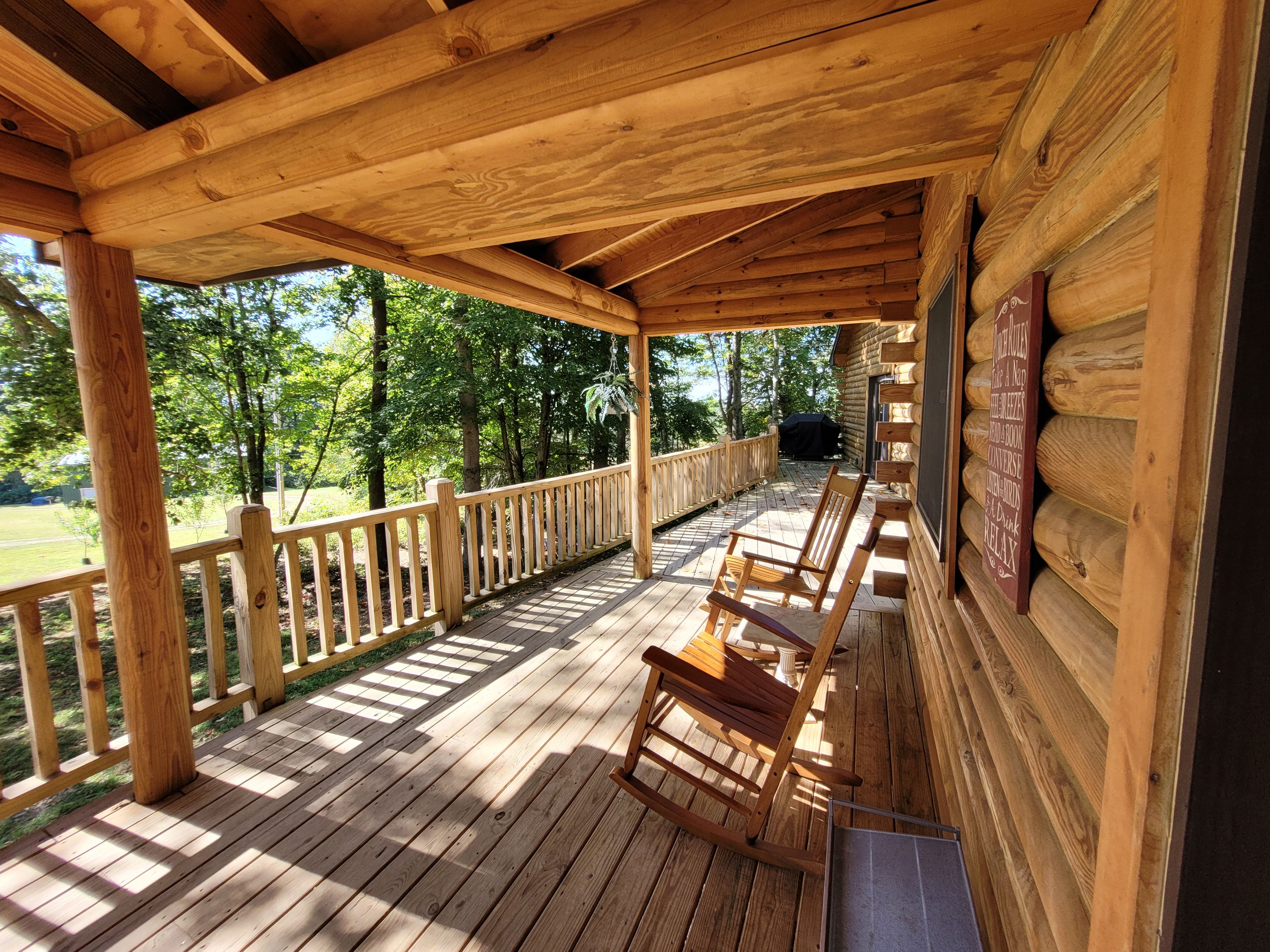 A wooden deck with a railing, a wooden chair, and a grill area.