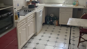 A compact kitchen with white cabinets, a stove, a sink, and a window with blinds. - Paris 12th (Paris)