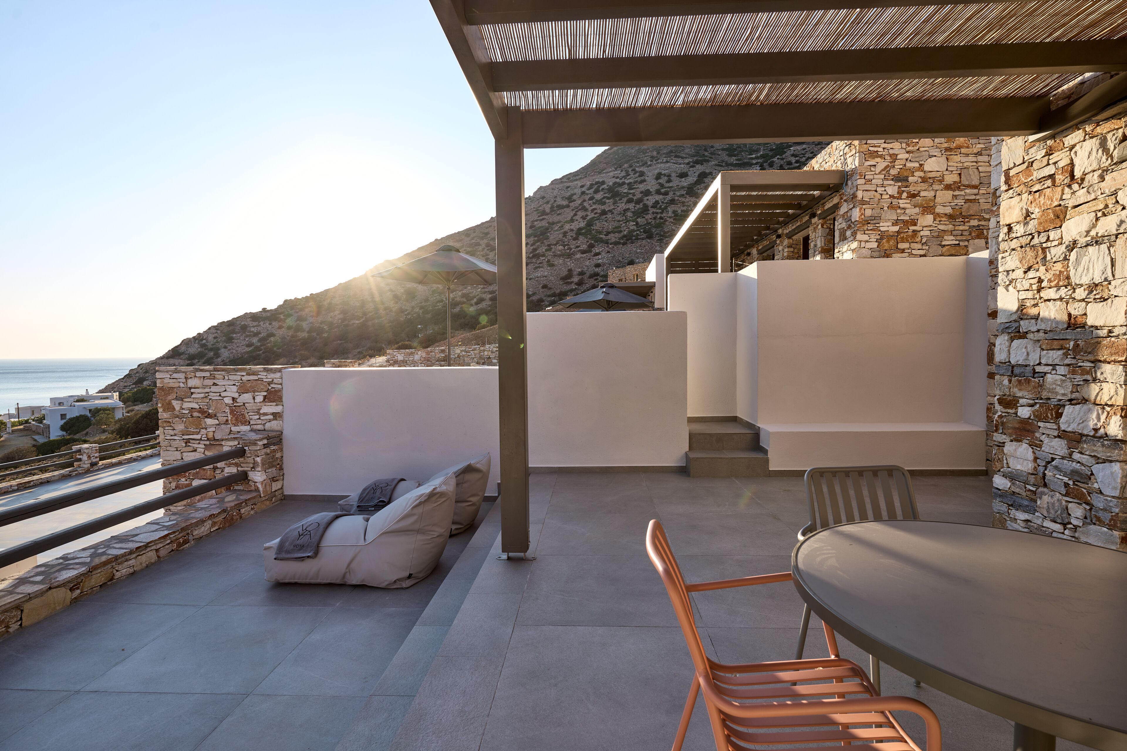 Eine moderne Außenpatio mit einer Steinmauer, einer gepolsterten Sitzgruppe und einem Tisch.