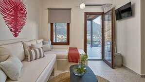 Un salon moderne avec un canapé, une porte vitrée donnant sur un balcon, un téléviseur à écran plat et une grande œuvre d’art représentant une feuille rouge accrochée au mur.