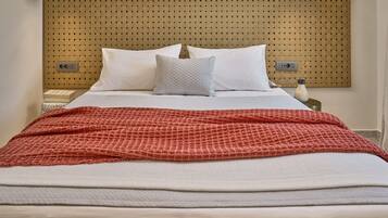 A neatly made bed with white and red bedding, a woven headboard, and bedside tables with lamps.