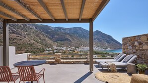 Un espace extérieur abrité, aménagé avec des sièges, et offrant une vue sur les montagnes et une ville côtière.