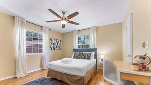 A bedroom with a bed, a desk, a chair, a globe, and a ceiling fan. - Eclectic Escape #2 - Team Joseph Ellen (Jacksonville)