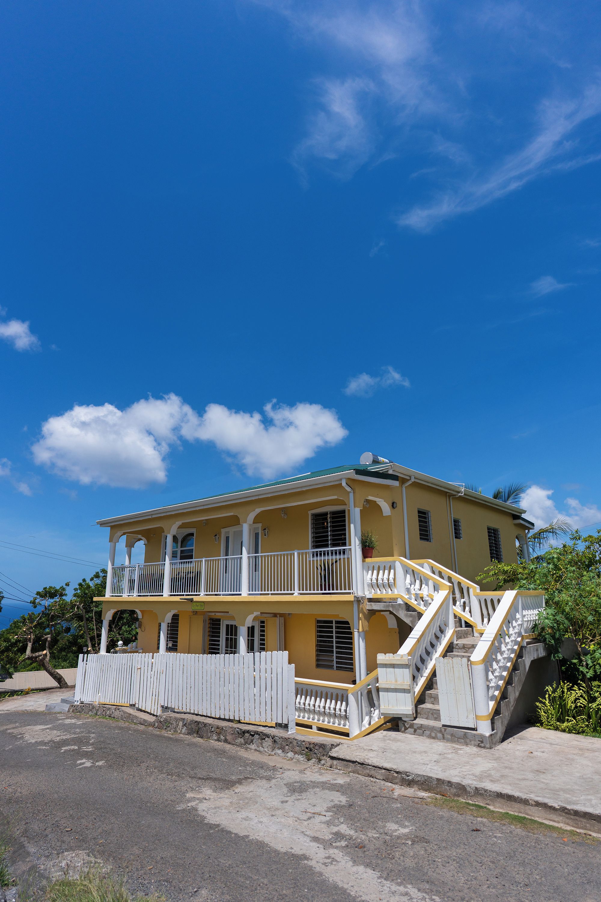 A two-story building with a balcony, a staircase, and a white picket fence.