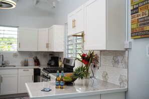 A kitchen with white cabinets, a coffee maker, and a pineapple on the counter.