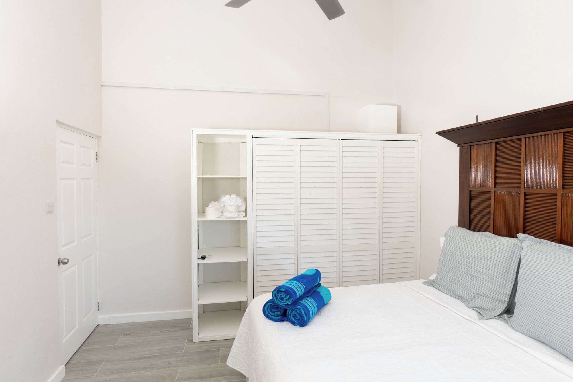A bedroom with a bed, a wardrobe, and a ceiling fan.