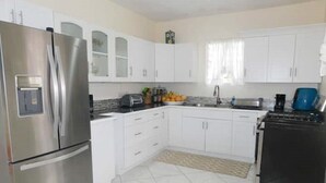 A modern kitchen with white cabinets, stainless steel appliances, and a tiled floor. - La Kayé Celesté your home away from home!! (Castries)