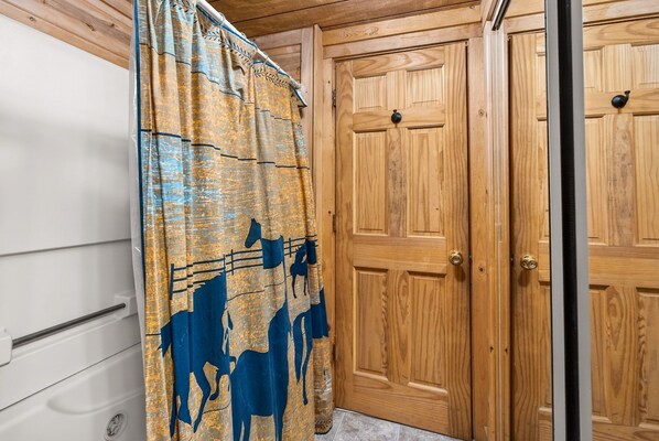 A wooden door with a metal handle, a curtain with a horse pattern, and a white appliance.