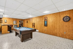 A pool table in a room with wooden walls, a dartboard, and a bar area. - Lazy Lane Cabins - Lane's End (Laurelville)