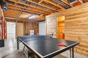 Une table de ping-pong dans une pièce dont les poutres en bois sont apparentes et qui possède un mur en bois.