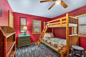 A bunk bed room with a ladder, a dresser, a lamp, and a poster on the wall. - Lazy Lane Cabins - Lane's End (Laurelville)