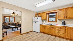 A kitchen with wooden cabinets, a refrigerator, and a coffee maker. - Lazy Lane Cabins - Lane's End (Laurelville)