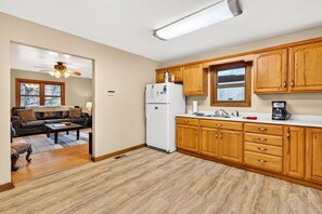 A kitchen with wooden cabinets, a refrigerator, and a coffee maker. - Lazy Lane Cabins - Lane's End (Laurelville)