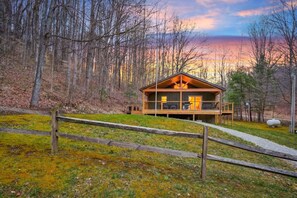 A cabin with a deck, surrounded by trees and a sunset view. - Lazy Lane Cabins - Lane's End (Laurelville)