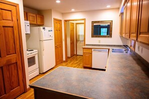 A kitchen with wooden cabinets, a refrigerator, an oven, a dishwasher, and a countertop.