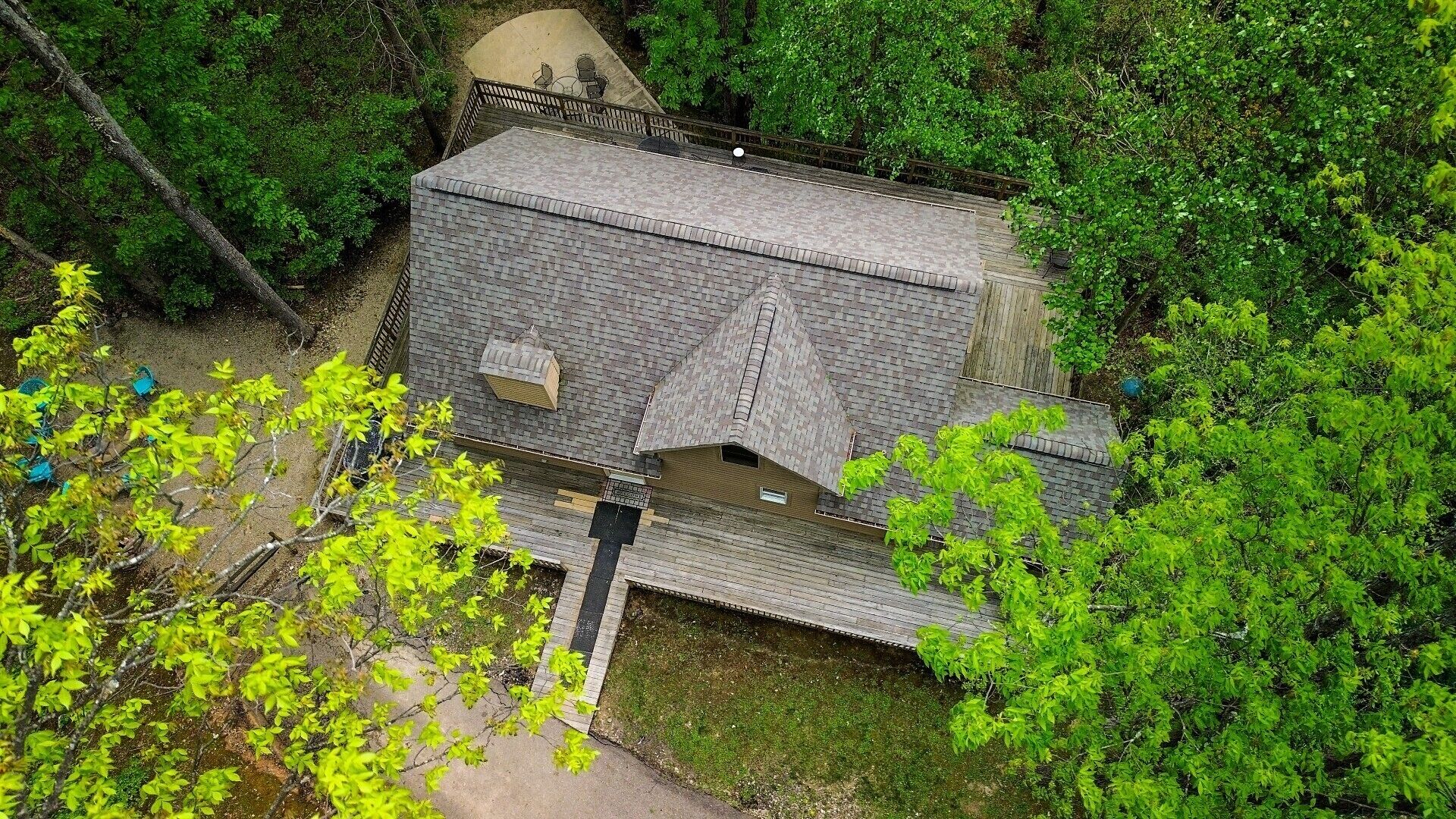 A house with a sloped roof, surrounded by dense green foliage.