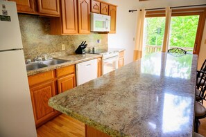Una cocina con encimeras de granito, armarios de madera, lavavajillas, microondas y estufa.
