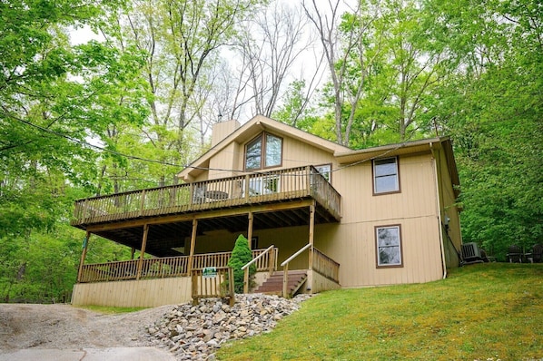 A two-story house with a balcony, a covered porch, and a stone foundation.