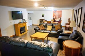 Una sala de estar con chimenea, sofás de cuero, una mesa de centro y televisor.