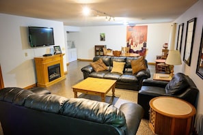 Una sala de estar con chimenea, sofás de cuero, una mesa de centro y televisor.