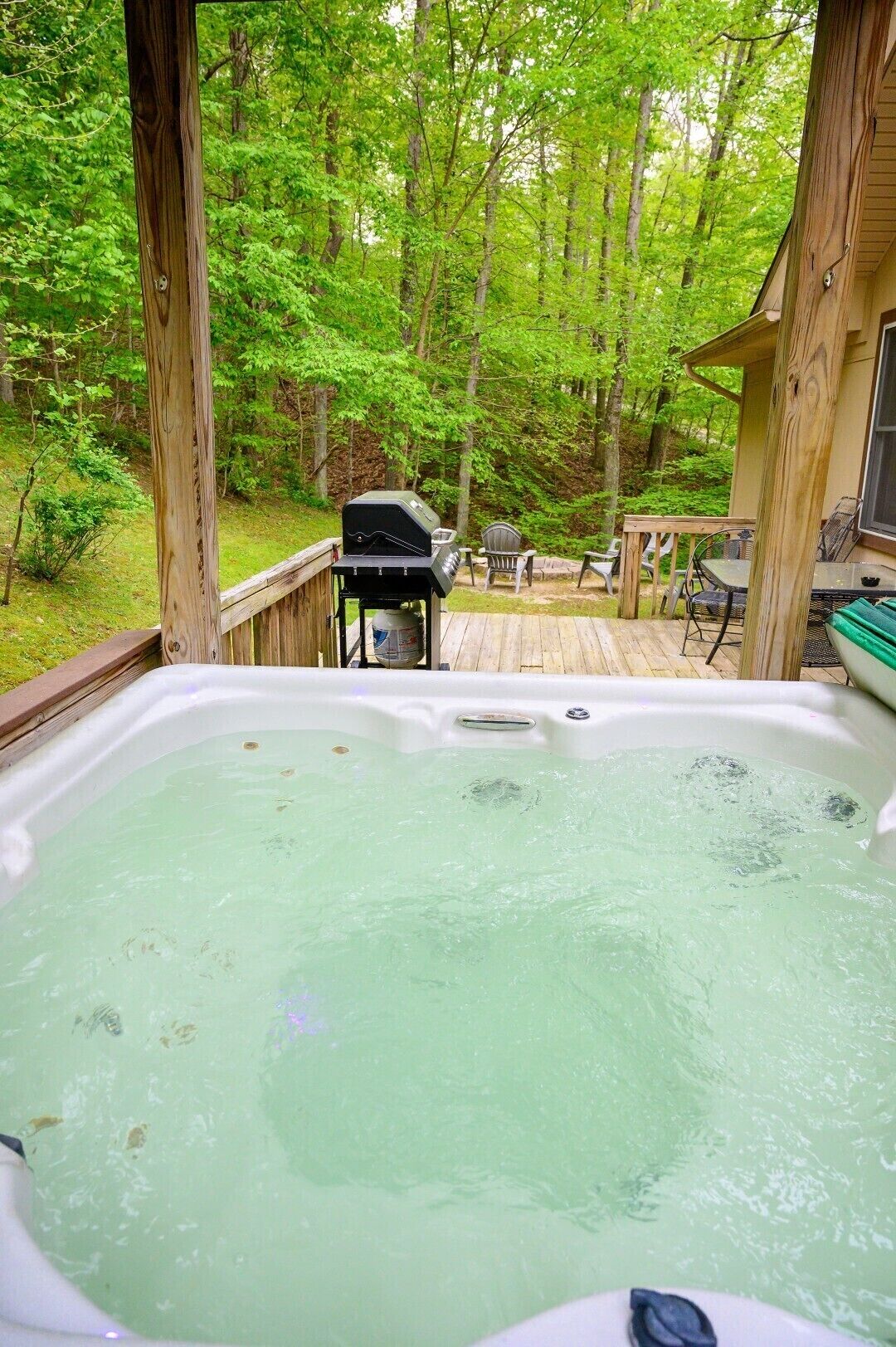 A hot tub on a wooden deck with a view of a forest.