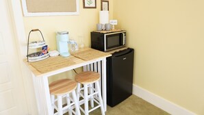 Cocina americana compacta con microondas, cafetera y taburetes de bar.