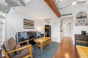 Ein Wohnzimmer mit einer Couch, einem Holztisch und einem gemusterten Teppich.