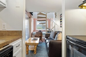 A modern interior with a wooden dining table, a leather sofa, and a staircase leading to an upper level.