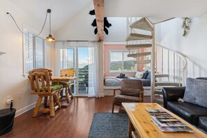 Een gezellige woonkamer met een houten tafel, stoelen, een bank en een kattenboom.