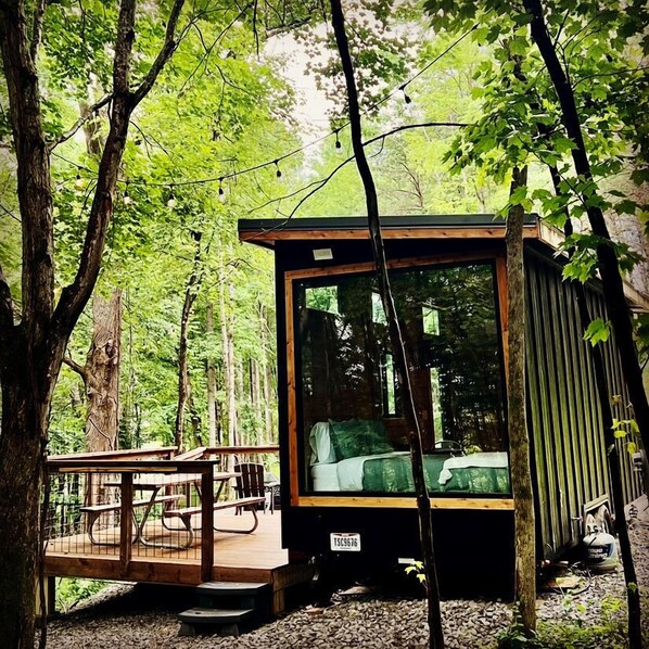 A small cabin with a wooden deck and a single bed.