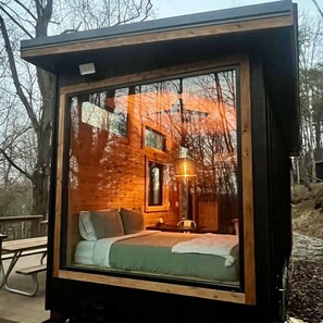 A cozy cabin-style room with a bed, a window, and a hanging light fixture.