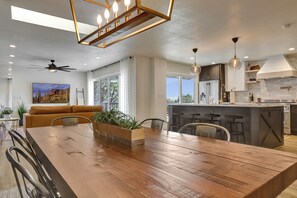Une cuisine moderne dotée d’un îlot central, de tabourets de bar et d’un coin repas avec une table et des chaises en bois.