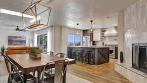Une cuisine moderne dotée d’un îlot central, d’un coin repas avec une table en bois et d’un espace salon confortable avec un canapé.