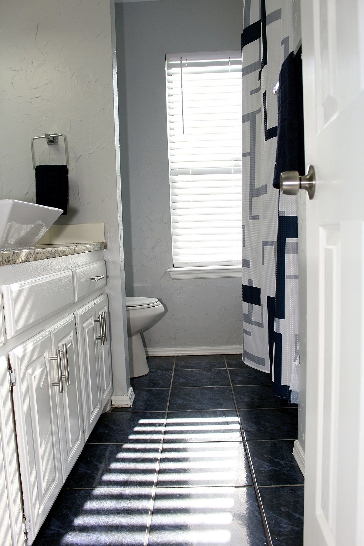 A bathroom with a toilet, a sink with a mirror, and a shower area.