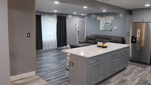 A modern kitchen with grey cabinets, a stainless steel refrigerator, and a central island.