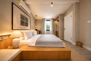 A bedroom with a bed, bedside table, lamp, and a framed artwork on the wall.