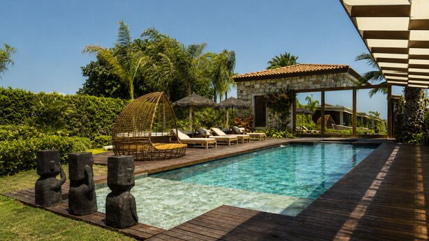 Une piscine avec des chaises longues et une structure en pierre en arrière-plan.