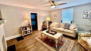 A living room with a beige sofa, a coffee table, a floor lamp, and a ceiling fan.