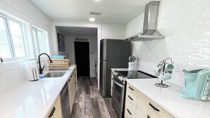 A modern kitchen with wooden cabinets, a stainless steel refrigerator, and a built-in oven.