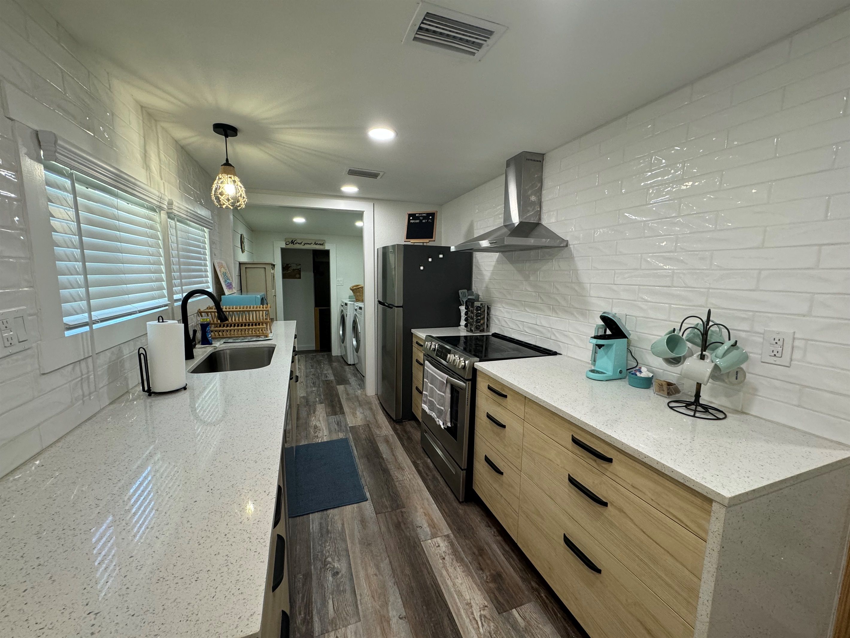 A modern kitchen with a stainless steel refrigerator, a built-in oven, and a coffee machine.