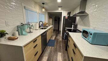 A modern kitchen with a central island, stainless steel appliances, and a blue microwave.