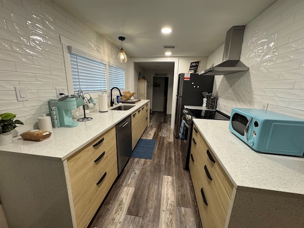 Una cocina moderna con una isla central, electrodomésticos de acero inoxidable y un microondas azul.