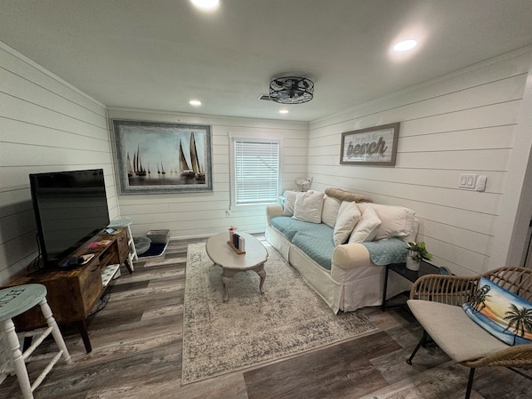 A living room with a television, a sofa, a coffee table, and a chair.