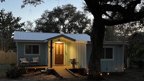 A small, single-story house with a front porch, a door, and a small deck area.