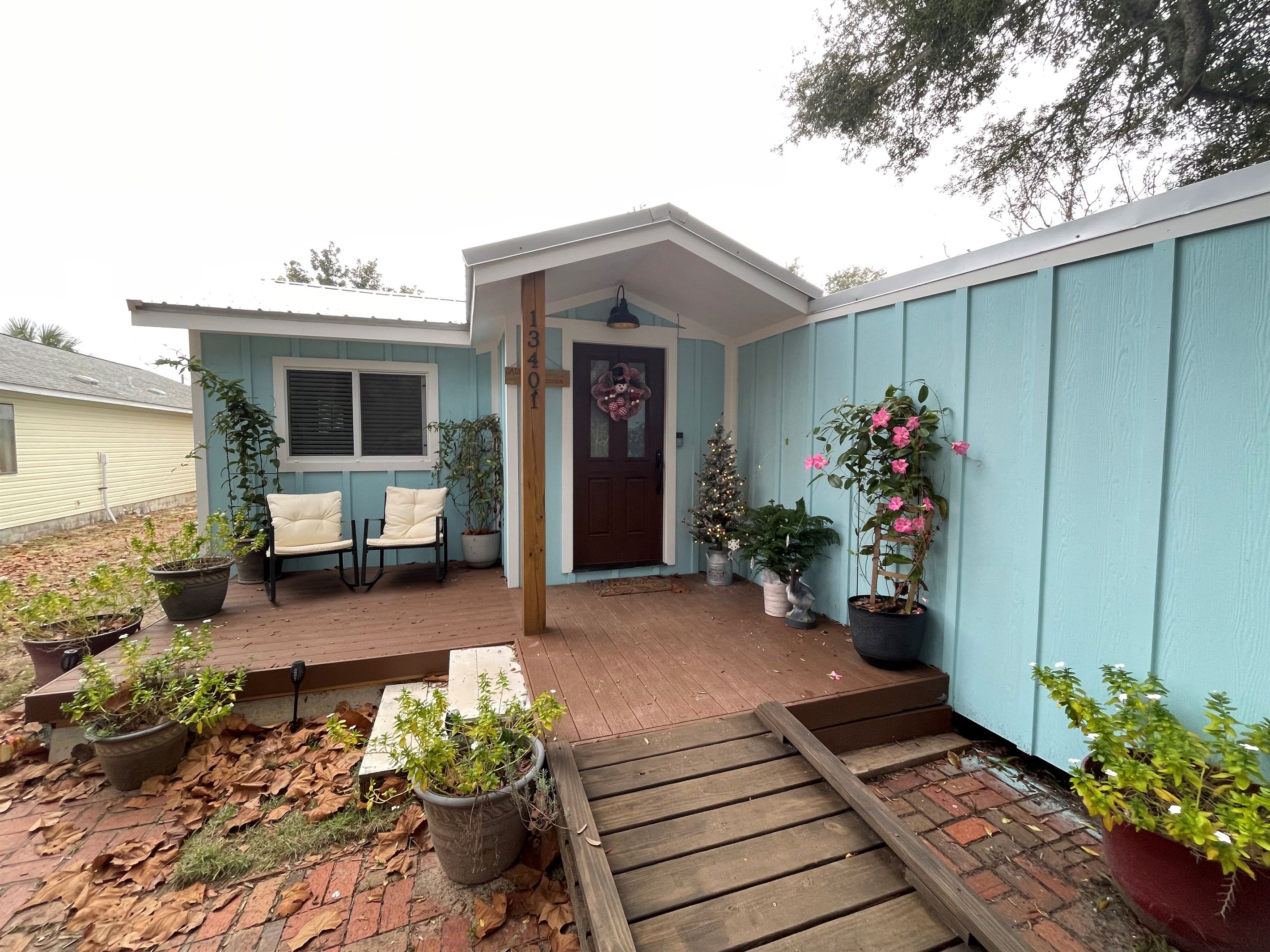 Una casa con porche, buzón y puerta decorada con un adorno navideño.